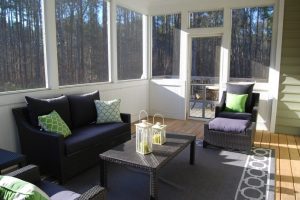 Sunroom with large windows and navy outdoor furniture with green pillows